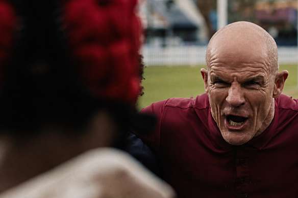 Ian Roberts in the music video, playing an angry footy coach.