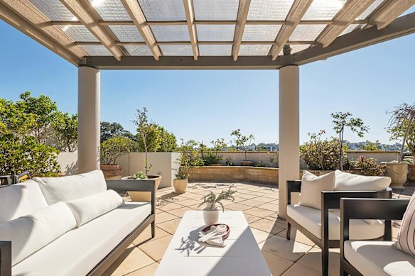 The outdoor space is suspended above the water and sheltered by a pergola.