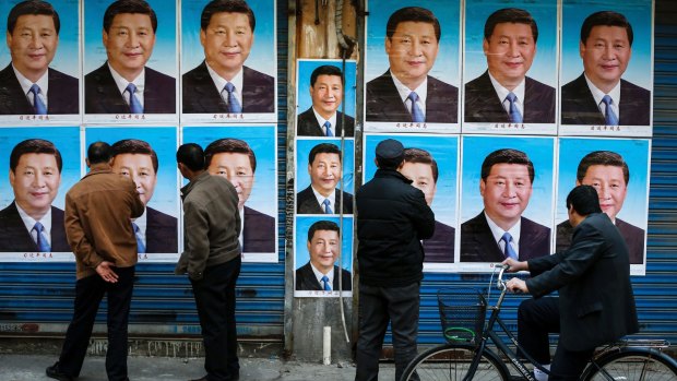 People look at a building covered in posters of Chinese President Xi Jinping in Shanghai. 