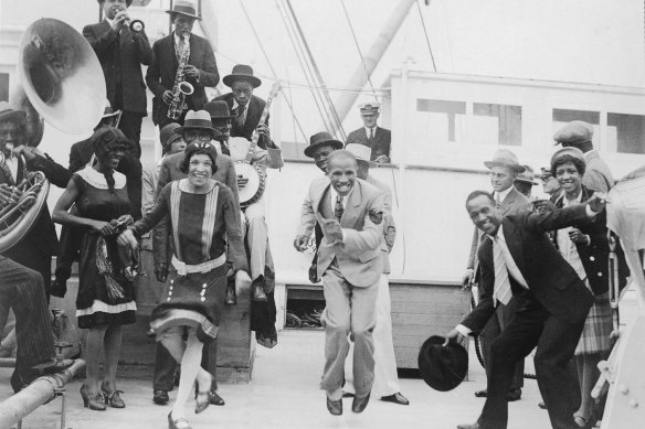 Sonny Clay’s Colored Idea jazz band with entourage including singer Ivy Anderson (left) singer and comedian Dick Saunders in the light suit, and Sonny Clay, holding the hat at right, arrives at Sydney’s Circular Quay in 1928. 