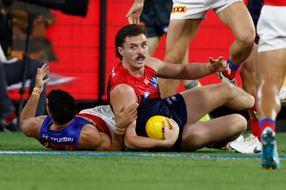 Jake Lever of the Demons is tackled by Charlie Cameron of the Lions.