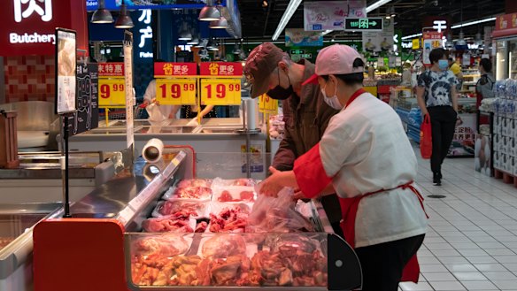 A saleswoman helps a customer choose meat at a Carrefour Superstore in Beijing. 