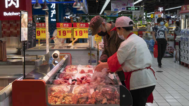 A saleswoman helps a customer choose meat at a Carrefour Superstore in Beijing. 