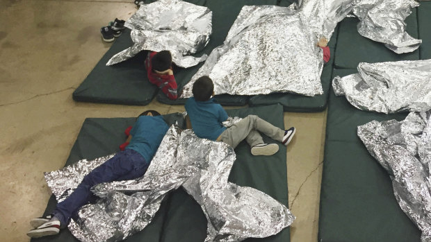 Teens who have been taken into custody on the US-Mexico border rest in one of the cages at a facility in McAllen, Texas.