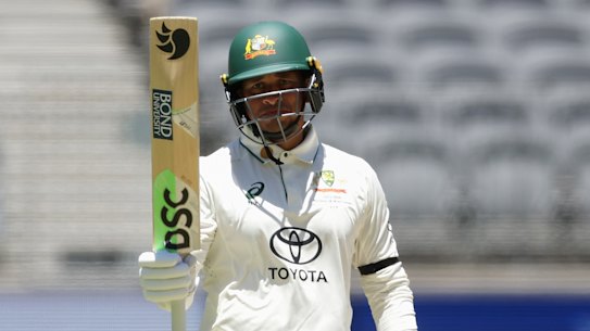 Khawaja raises the bat after reaching his half-century.