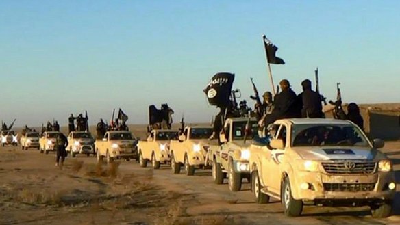 In this undated file photo released online in the summer of 2014 on a militant social media account,  militants of the Islamic State group hold up their weapons and wave its flags on their vehicles in a convoy on a road leading to Iraq, in Raqqa, Syria. 