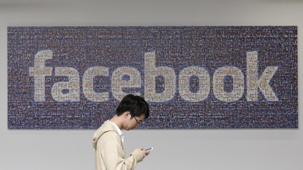 A man walks past a Facebook sign in an office on the Facebook campus in Menlo Park, California. 