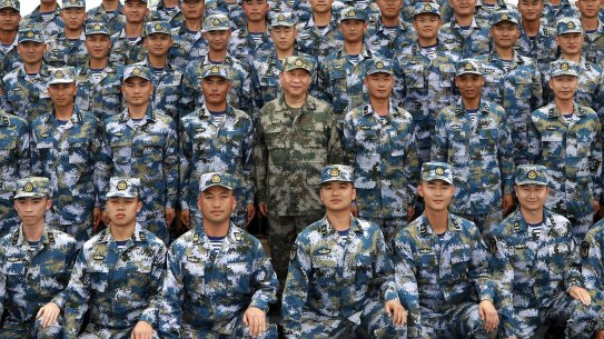 Chinese President Xi Jinping (centre in green military uniform) poses with soldiers on a navy ship in 2018.