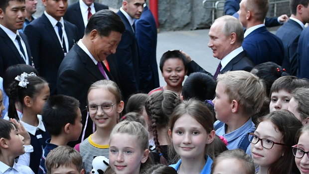 Chinese President Xi Jinping, centre left, and Russian President Vladimir Putin, centre right, at the Moscow Zoo with school children to mark the handover of two pandas to Moscow.
