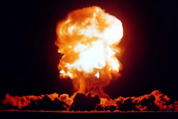A nuclear explosion sends a mushroom cloud up into the sky.