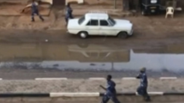 Police officers run down a street in Khartoum, Sudan, on Monday.