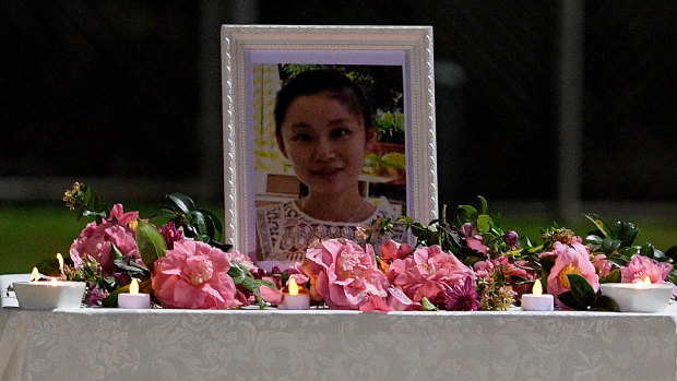 Flowers and candles are placed by a framed photo of missing woman Qi Yu at a community gathering on Friday night. 