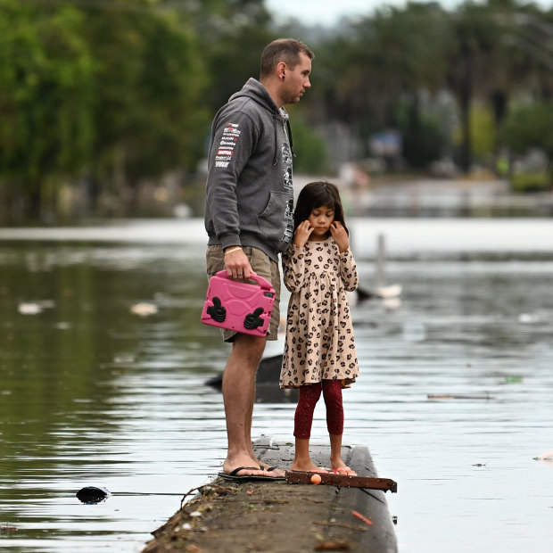 A father and daughter inspect a flooded Lismore street in March 2022.