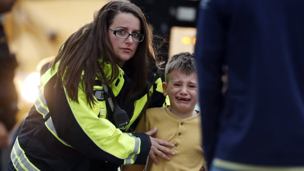 Officials guide students off a bus to be reunited with their parents after a shooting at a suburban Denver school.