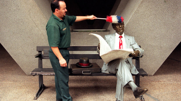 A cleaner dusts off Seward Johnson's "Waiting" at Australia Square in Sydney.
