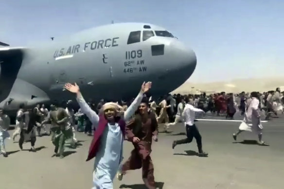Chaos on the tarmac: hundreds of people run alongside a US Air Force C-17 transport plane as it moves down a runway in Kabul after the city fell to the Taliban.