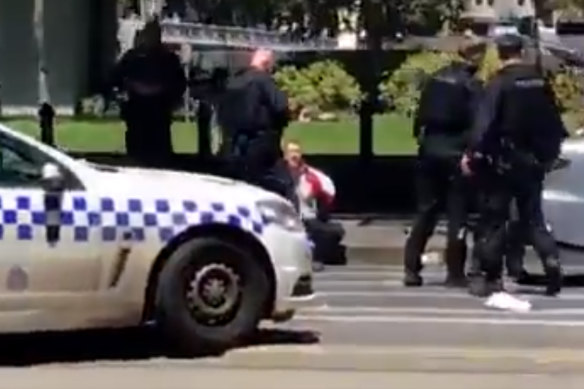 Police arrest a man at the corner of Flinders and William streets.