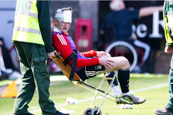 Aberdeen player Jack Mackenzie is wheeled from the field after being struck by the seat thrown by a fan.