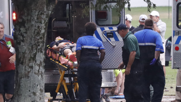 Felled: An injured golf fan is loaded into an ambulance after being struck by lightning near the practice range.