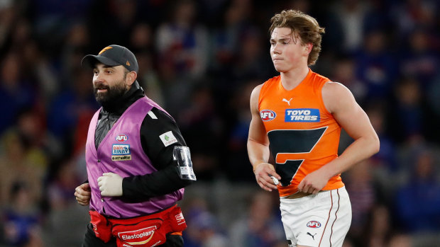 Tanner Bruhn leaves the field with a member of the GWS medical staff.