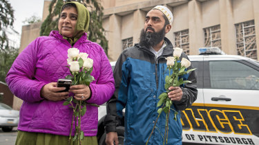 Samina Mohamedali, left, and her husband Kutub Ganiwalla, members of the Dawoodi Bohra Muslim community, both of North Hills, prepare to place flowers on a memorial in front of the Tree of Life Congregation on Sunday.