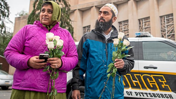 Samina Mohamedali, left, and her husband Kutub Ganiwalla, members of the Dawoodi Bohra Muslim community, both of North Hills, prepare to place flowers on a memorial in front of the Tree of Life Congregation on Sunday.