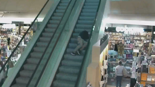 A Dymocks employee lies unconscious on an escalator after being pushed by a customer.