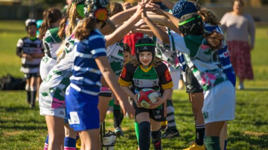 Girls run through a tunnel at the Frosty 7’s Girls Rugby tournament.