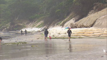 People walk along a beach in Byron Bay.