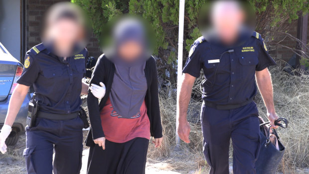 A woman being led away by border force officers.