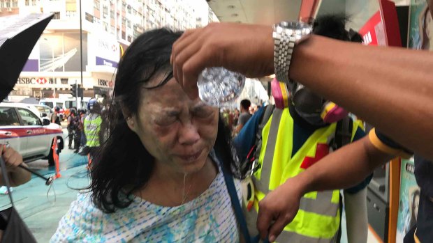 A woman gets help to wash pepper spray from her face.