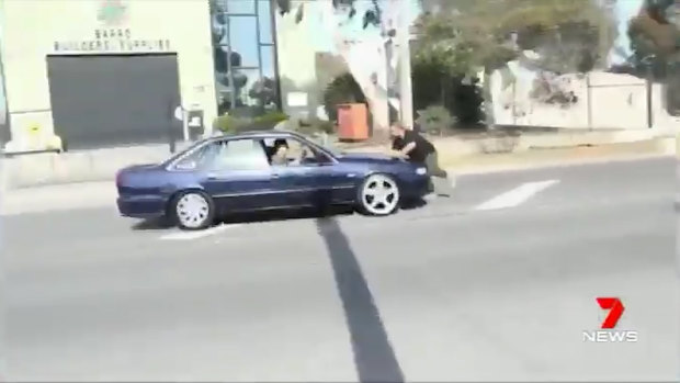 The victim tries to escape as the car drives towards him. 