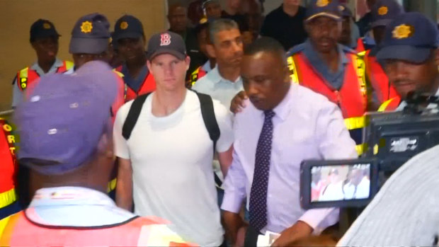 Centre of attention: There were chaotic scenes as Steve Smith was lead through Johannesburg Airport.