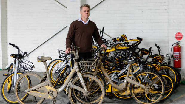 City of Melbourne deputy mayor Arron Wood standing with impounded oBikes. 