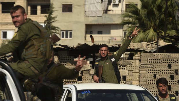 Kurdish men belonging to Asayish, the internal security force, make the peace sign on the streets of Qamishli in north-east Syria.