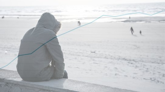 A person wearing a parka coat sits on a wall looking out at the sea Mental health mental illness depression loneliness suicide generic teenager child abuse composite with a graph showing indigenous children in child protection. 
