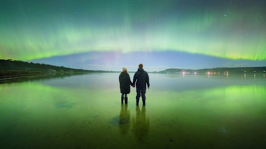 O céu é o limite: Esta foto de duas pessoas observando a Aurora Austral iluminar uma praia no sul da Tasmânia por volta das 5h de sábado foi tirada com uma câmera digital.