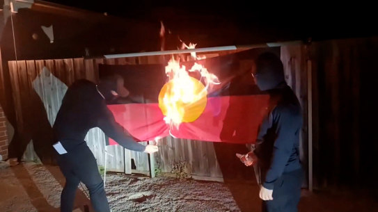 A still from a video posted online by a neo-Nazi group of them burning the Aboriginal flag.