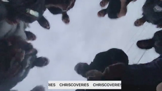 A crowd surrounds a man who had been pushed to the ground.