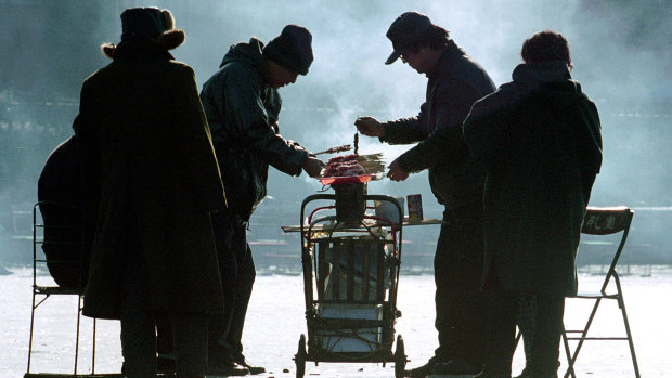 Customers brave clouds of smoke to buy lamb skewers from a vendor with a mobile stall on the ice of a frozen lake in Beijing.