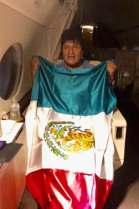 Bolivia's former president Evo Morales holding a Mexican flag aboard a Mexican Air Force aircraft as he flees after resigning.