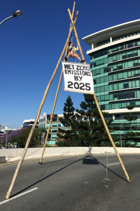 Extinction Rebellion activist Rilka is suspended from a bamboo tripod over a Milton motorway bypass in Brisbane, blocking traffic on Wednesday morning.
