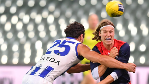 Crunch time: Melbourne's Ed Langdon handballs out ahead of a Tom McDonald tackle.