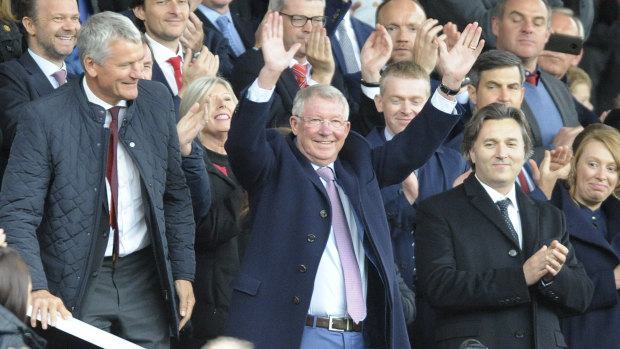 He's back: Former Manchester United manager Alex Ferguson waves as he takes his seat at Old Trafford.