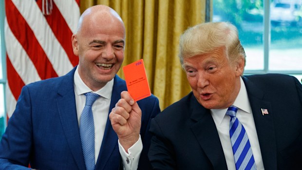 President Donald Trump holds up a red card during a meeting with FIFA president Gianni Infantino.