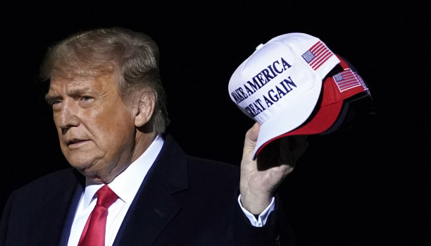 Again? Donald Trump armed with Make America Great Again hats, which he threw to supporters after speaking at a campaign rally in Minnesota on Wednesday. 
