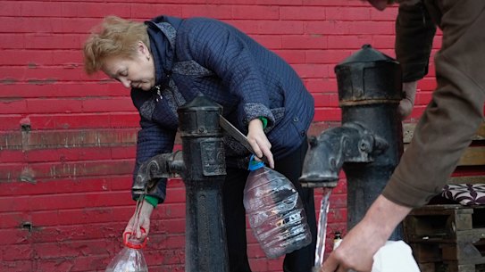 People fill containers with water from public water pumps in Kyiv, Ukraine, on Monday.