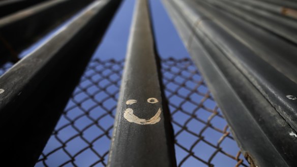 Graffiti adorns metal bars marking the United States border where it meets the Pacific Ocean.