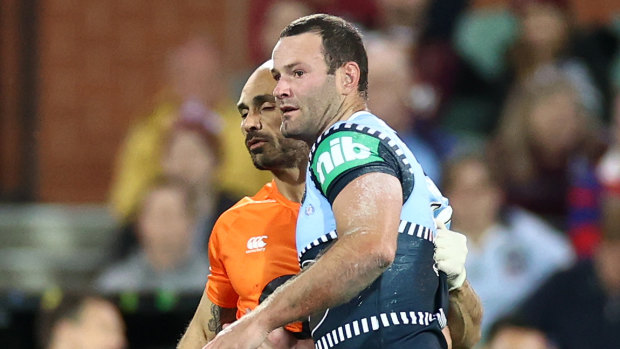 Boyd Cordner is helped from the field by Roosters and Blues trainer Travis Touma.