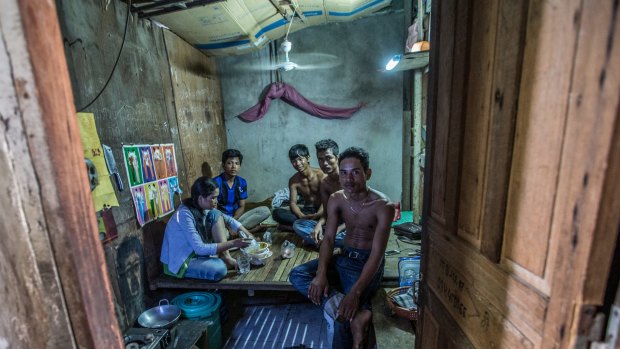 Oem Mom, 33, (woman pictured) sleeps on a wooden bench with four other family members in a tiny room made of scrap timber and cardboard off a dank alleyway near the Phnom Penh factory  in Cambodia. 